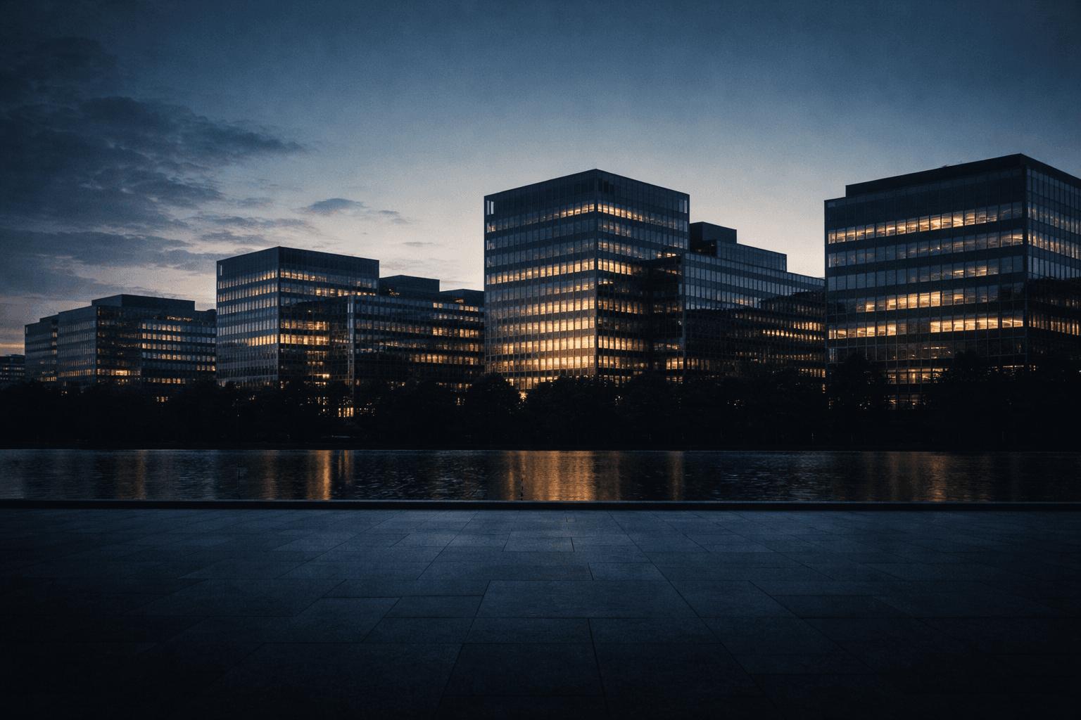 Silhouetted modern institutional buildings at dusk across the upper two thirds, with a calm empty forecourt in soft focus filling the lower third.